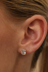 Gold Adamas oval stud worn on an ear — a 1.25 carat oval cubic zirconia in a four-prong setting.
