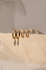 Grace Dangle GOLD Earring Set in 18K gold‑plated sterling silver with marquise‑cut cubic zirconia, elegant hoop design on beige surface