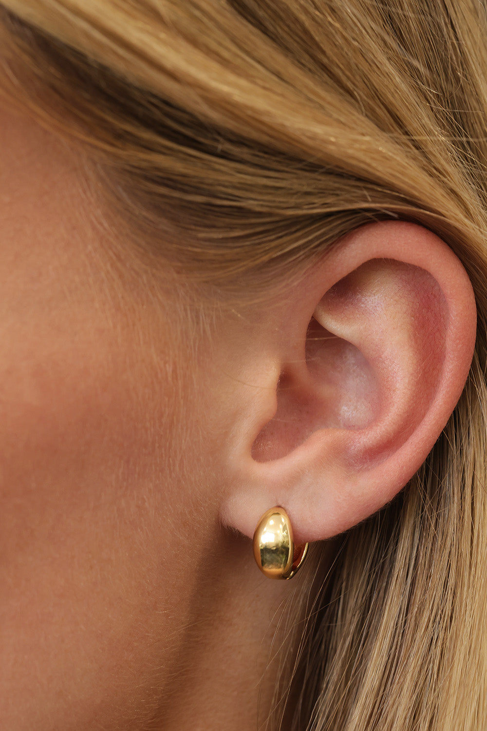 Gold Cleo huggie hoop earrings — close view of the smooth dome and 9mm hoop opening.
