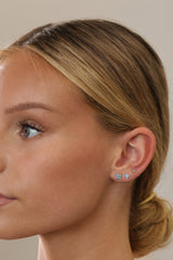 Model wearing gold 4 clover blue stud earrings stacked in three sizes on one ear, side profile