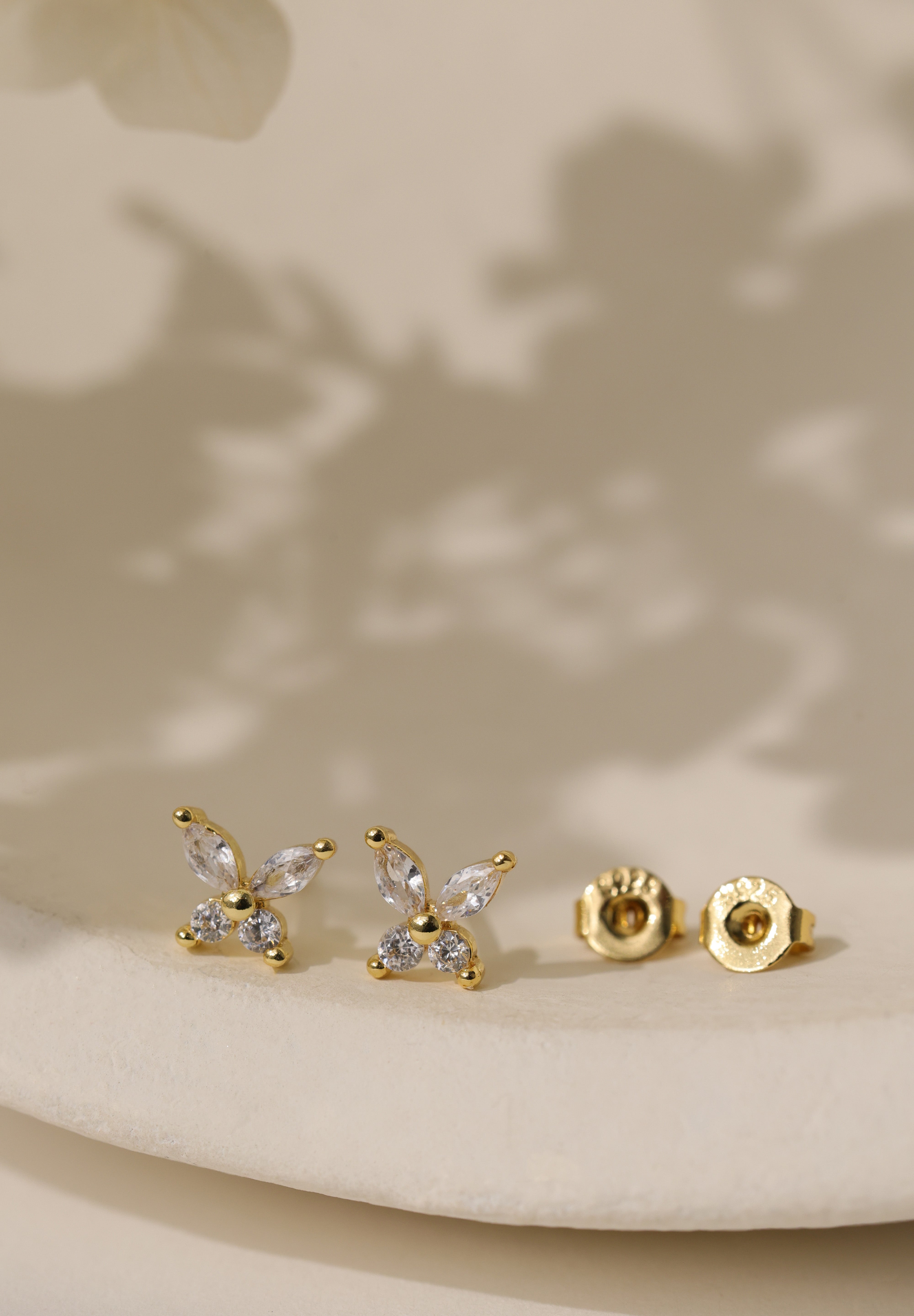 Gold-plated butterfly stud earrings set with four cubic zirconia stones, on a sterling silver base.