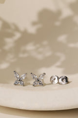 Sterling silver butterfly cubic zirconia stud earrings on a cream dish beside their 925 butterfly backs.