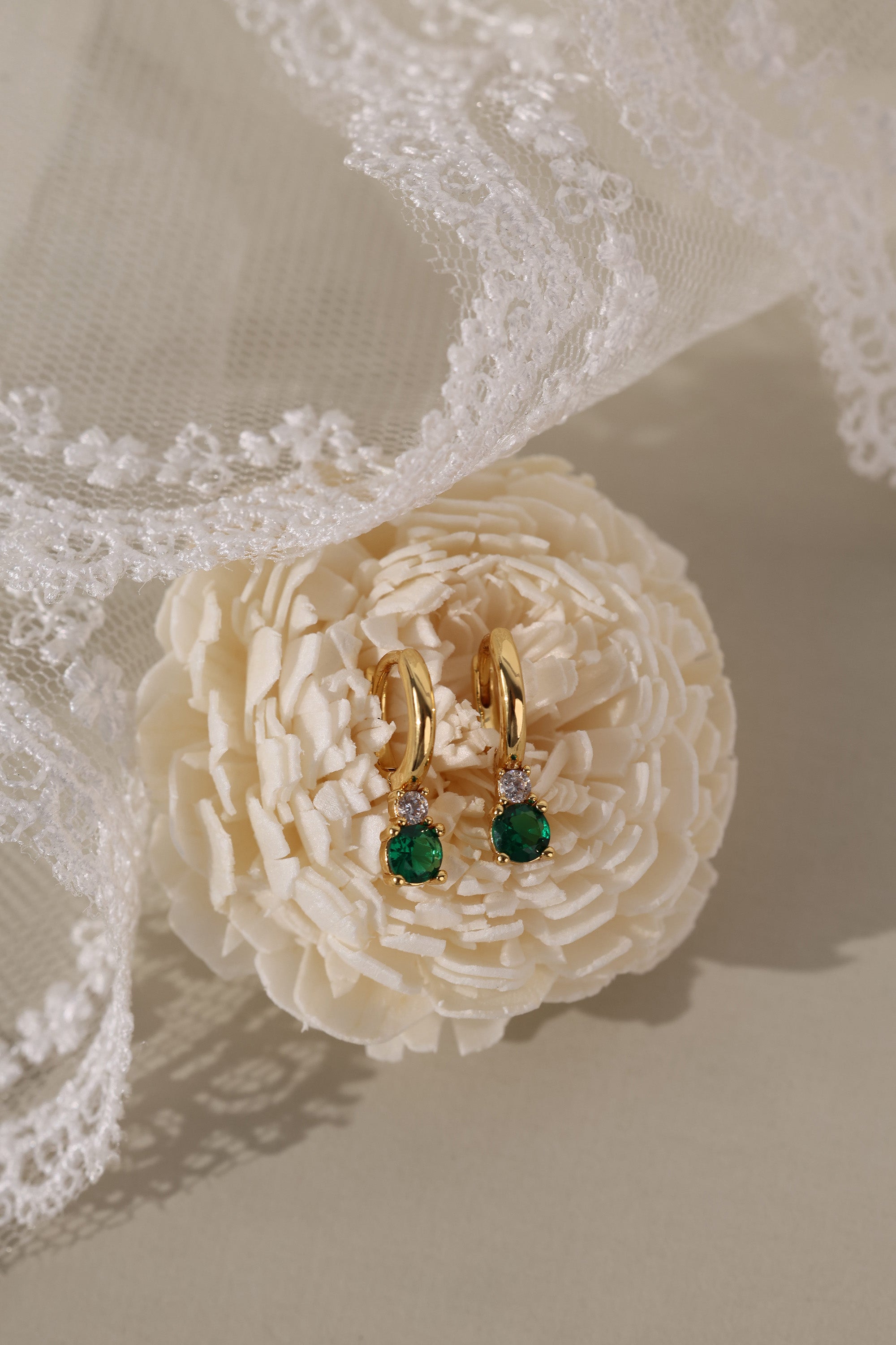 Gold hoop earrings with colorful gemstones in pink, clear, black, purple, green, and black.