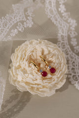 Gold hoop earrings with colorful gemstones in pink, clear, black, purple, green, and black.