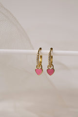 Dainty gold–plated hoop earrings with pave cubic zirconia and a removable heart charm, shown in four colour variations, available in gold and silver finishes.