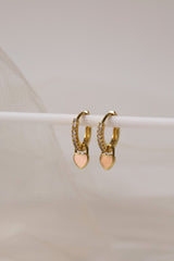 Dainty gold–plated hoop earrings with pave cubic zirconia and a removable heart charm, shown in four colour variations, available in gold and silver finishes.