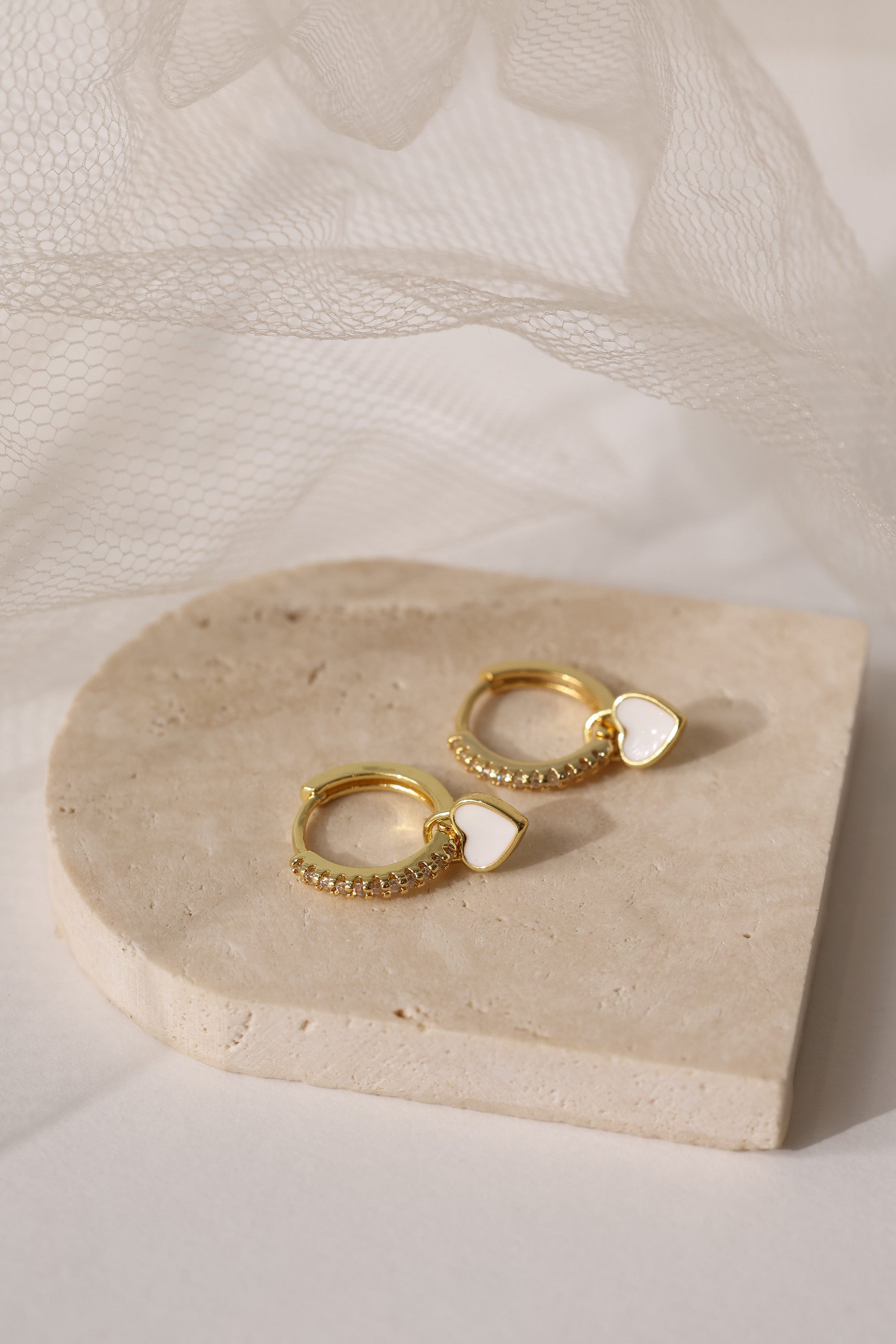 Dainty white gold–plated hoop earrings with pave cubic zirconia and a removable heart charm, shown in four colour variations, available in gold and silver finishes.