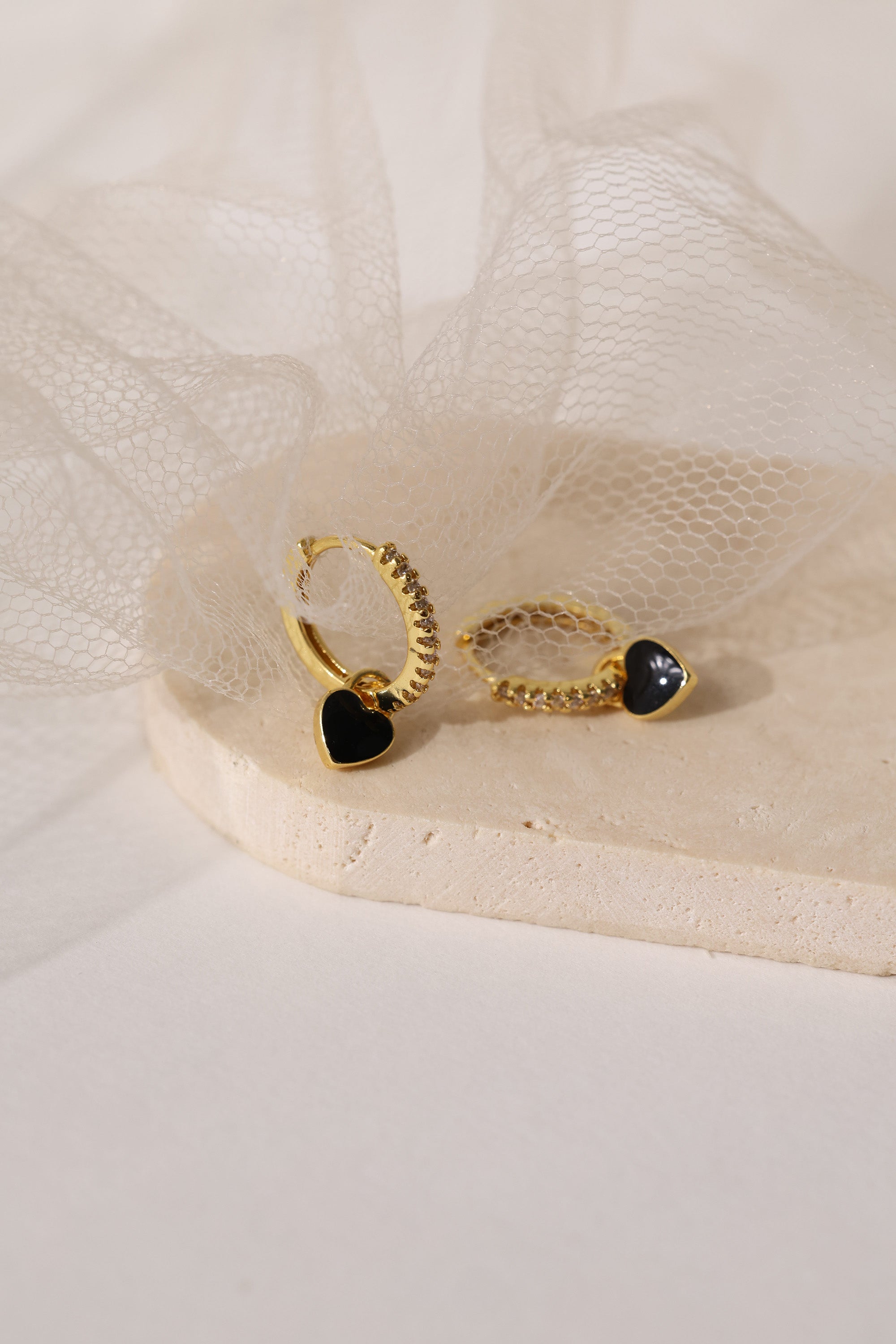 Dainty gold–plated hoop earrings with pave cubic zirconia and a removable heart charm, shown in four colour variations, available in gold and silver finishes.