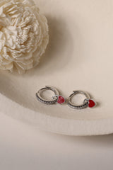 Dainty white gold–plated hoop earrings with pave cubic zirconia and a removable heart charm, shown in four colour variations, available in gold and silver finishes.