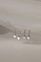 Dainty white gold–plated hoop earrings with pave cubic zirconia and a removable heart charm, shown in four colour variations, available in gold and silver finishes.