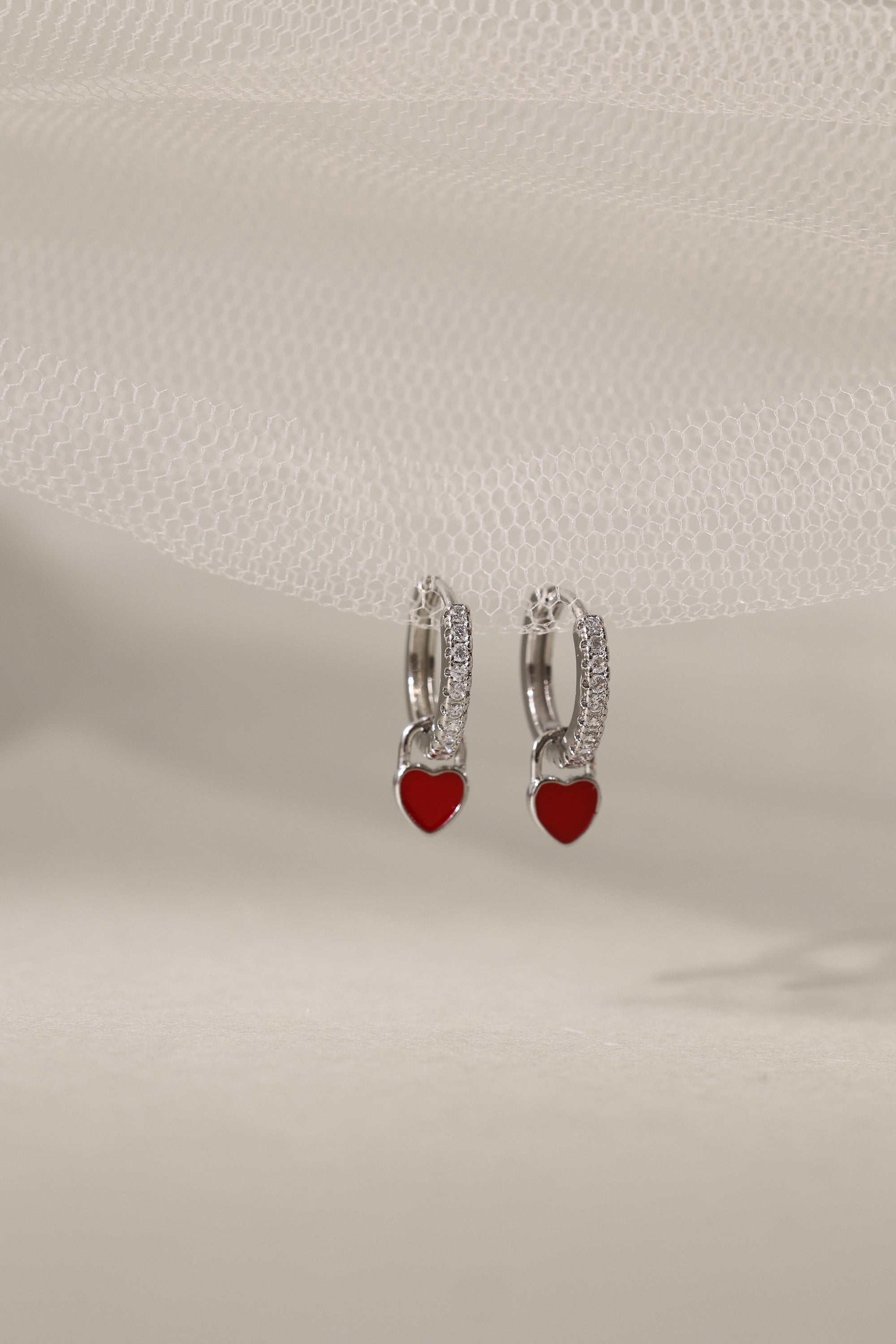Dainty white gold–plated hoop earrings with pave cubic zirconia and a removable heart charm, shown in four colour variations, available in gold and silver finishes.