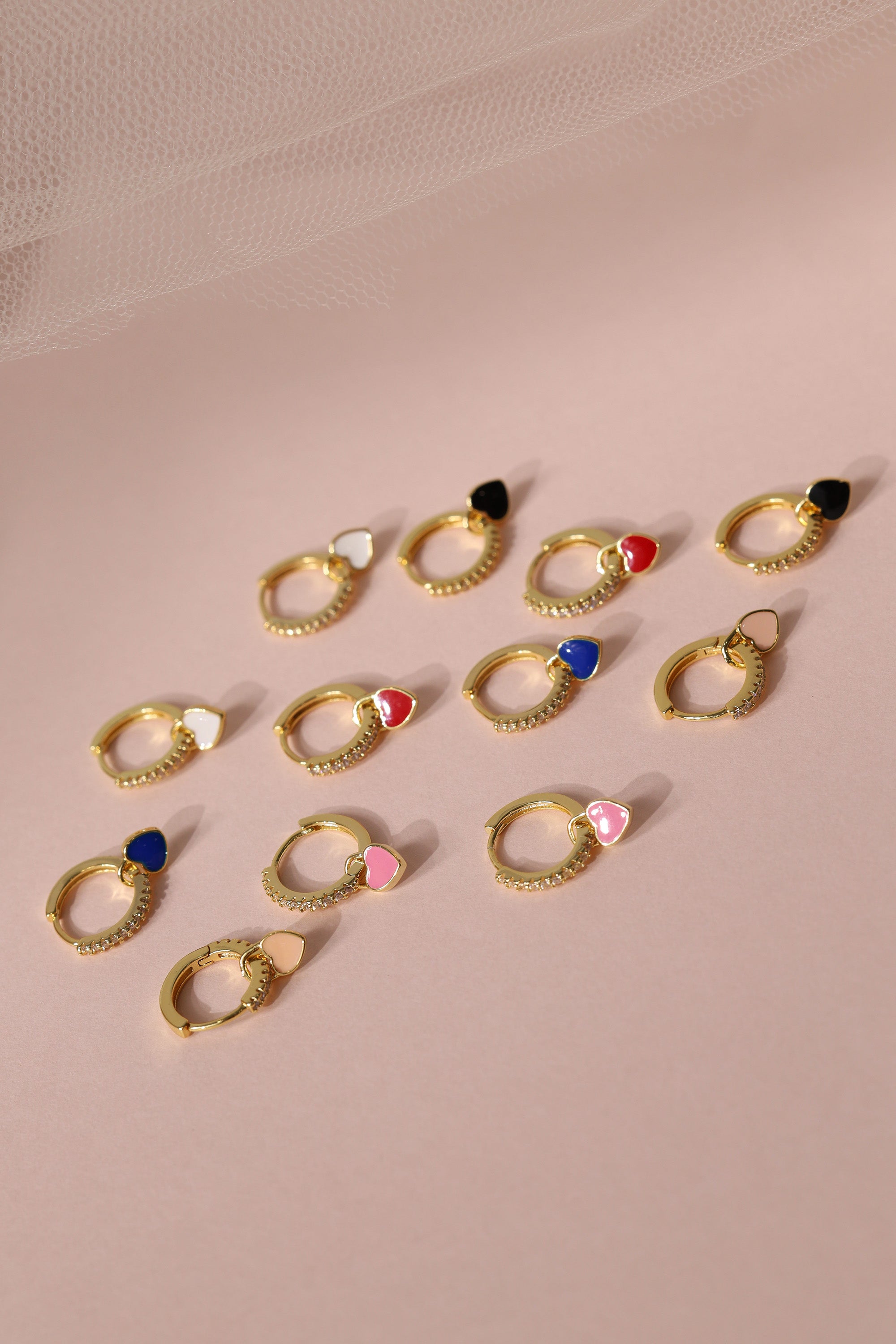 Dainty white gold–plated hoop earrings with pave cubic zirconia and a removable heart charm, shown in four colour variations, available in gold and silver finishes.