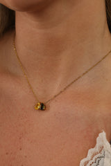 Woman wearing a personalised gold birthstone pendant necklace with pear-cut cubic zirconia stones