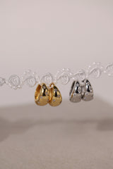 Gleaming silver hoop earrings with delicate star‑shaped engravings along the surface, reflecting light for a subtle sparkle; lightweight design shown in close‑up on a plain background.