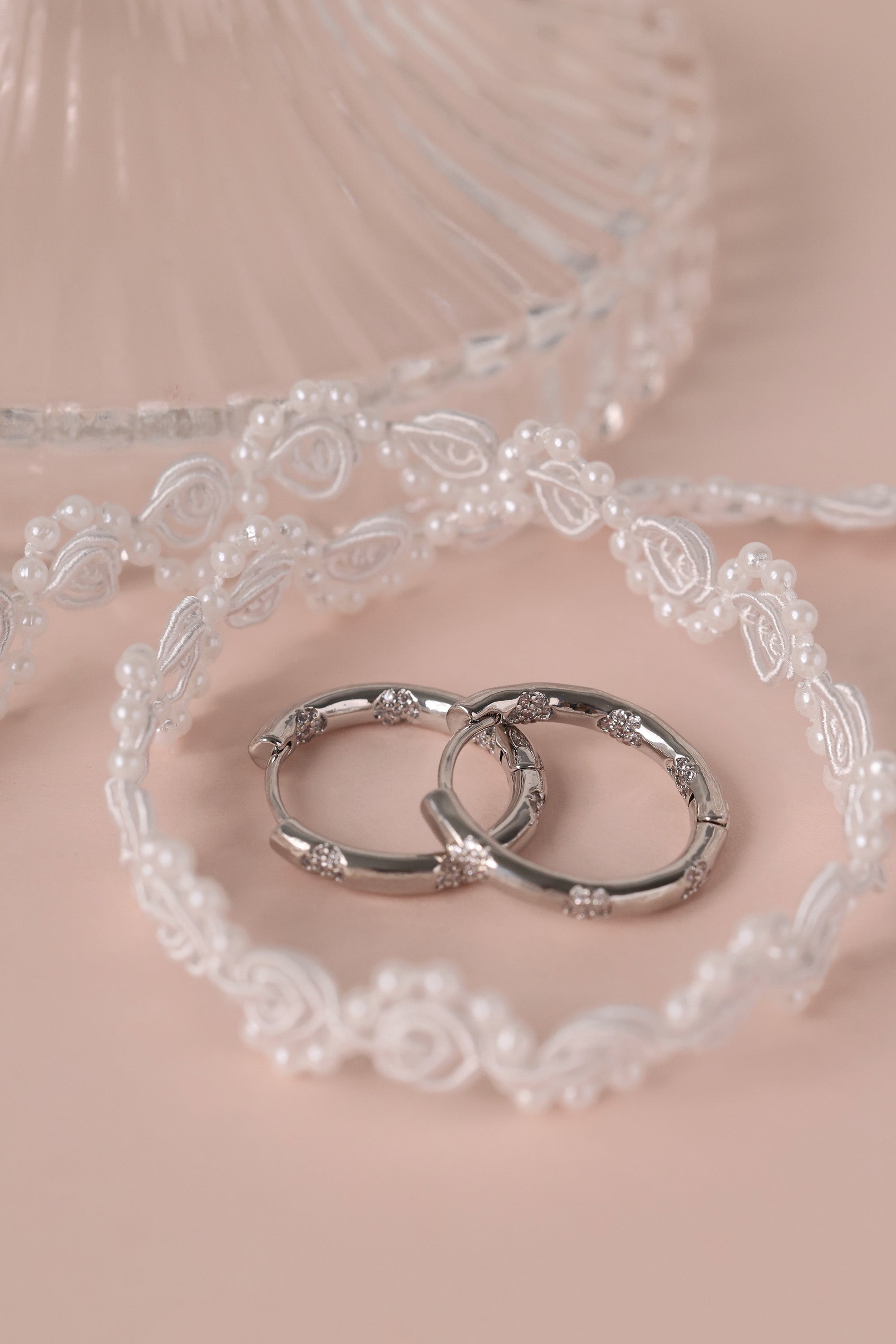 These elegant silver hoop earrings are meticulously crafted from brass with white gold plated featuring intricate floral inlaid cubic zirconia detailing in both inside and outside of the hoops.