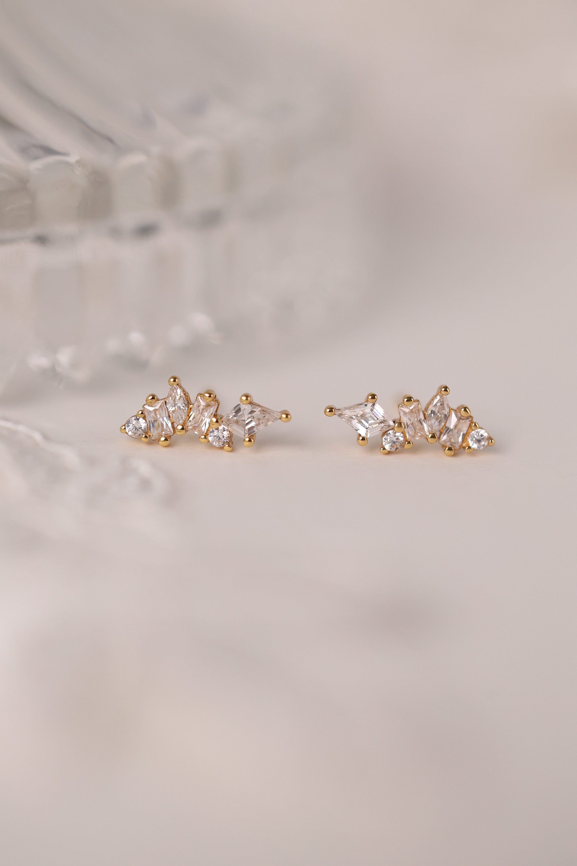 Pair of gold earrings with clear gemstones on a light background