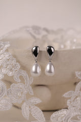 Stainless steel stud drop earrings with a large teardrop pearl worn on the ear.
