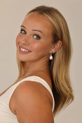 Stainless steel stud drop earrings with a large teardrop pearl worn on the ear.