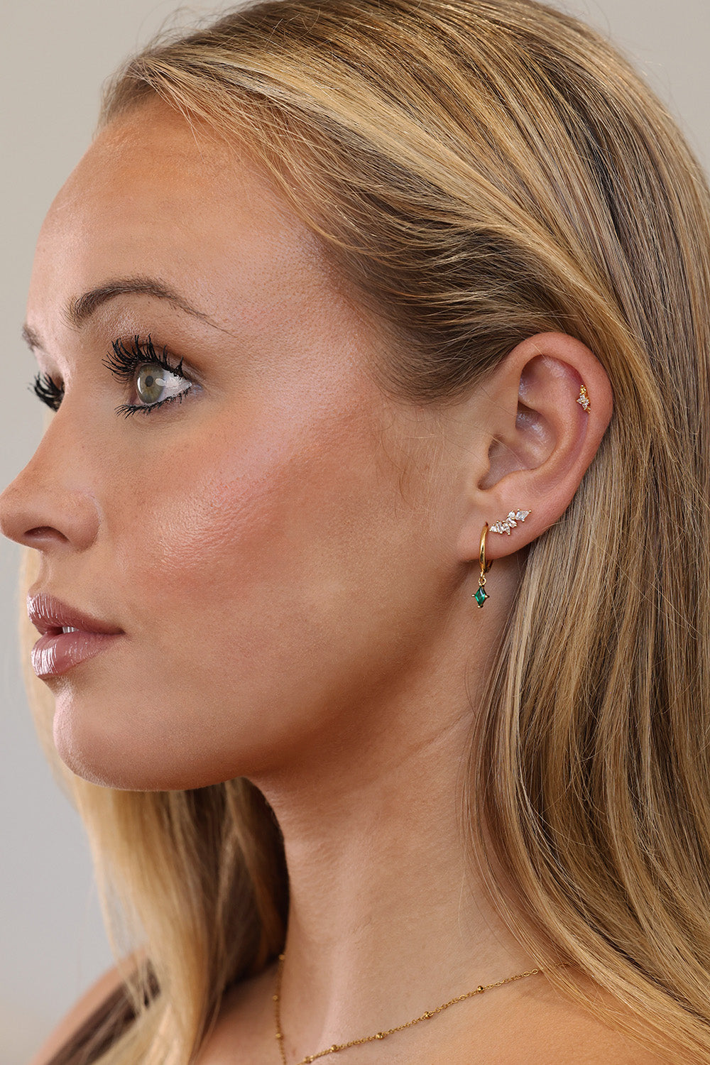 Green gemstone and clear stone sterling silver ear stack on model