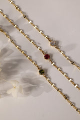 Gold stainless steel birthstone bracelet with a dainty chain and a single bezel‑set gemstone charm hanging at the centre.