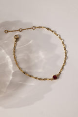 Gold stainless steel birthstone bracelet with a dainty chain and a single bezel‑set gemstone charm hanging at the centre.