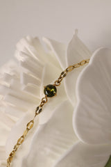 Gold stainless steel birthstone bracelet with a dainty chain and a single bezel‑set gemstone charm hanging at the centre.