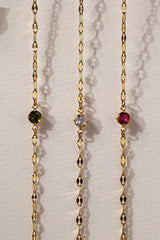 Gold stainless steel birthstone bracelet with a dainty chain and a single bezel‑set gemstone charm hanging at the centre.
