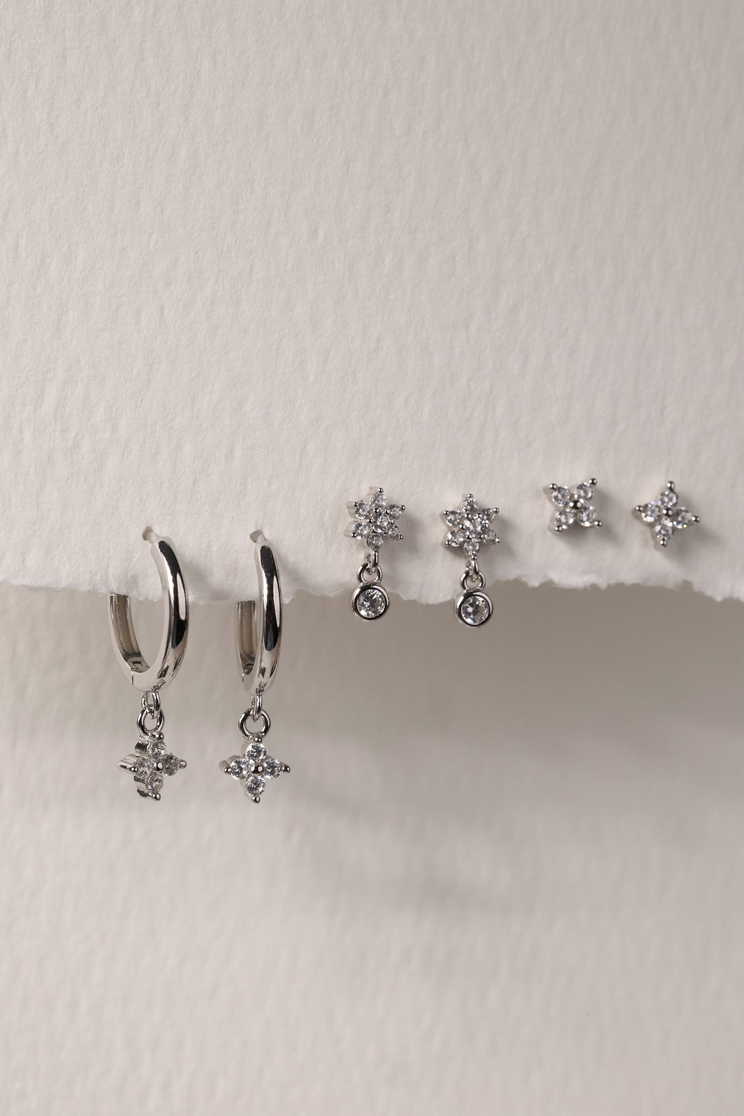 Small silver clover earring set with dangle, snowflake stud, and mini clover stud displayed on a clean background.”