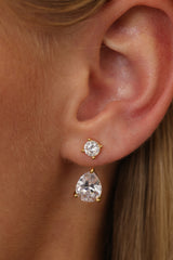 Close-up of the gold Adamas ear jacket on an ear — round stud above a 2 carat pear-cut cubic zirconia drop.