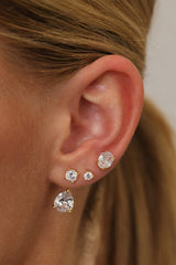 Gold Adamas ear stack — 1.25 carat oval stud on the upper lobe with two round studs and the pear-cut drop.