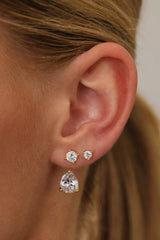 Gold Adamas ear jacket worn with two round cubic zirconia studs above the pear-cut drop on one lobe.