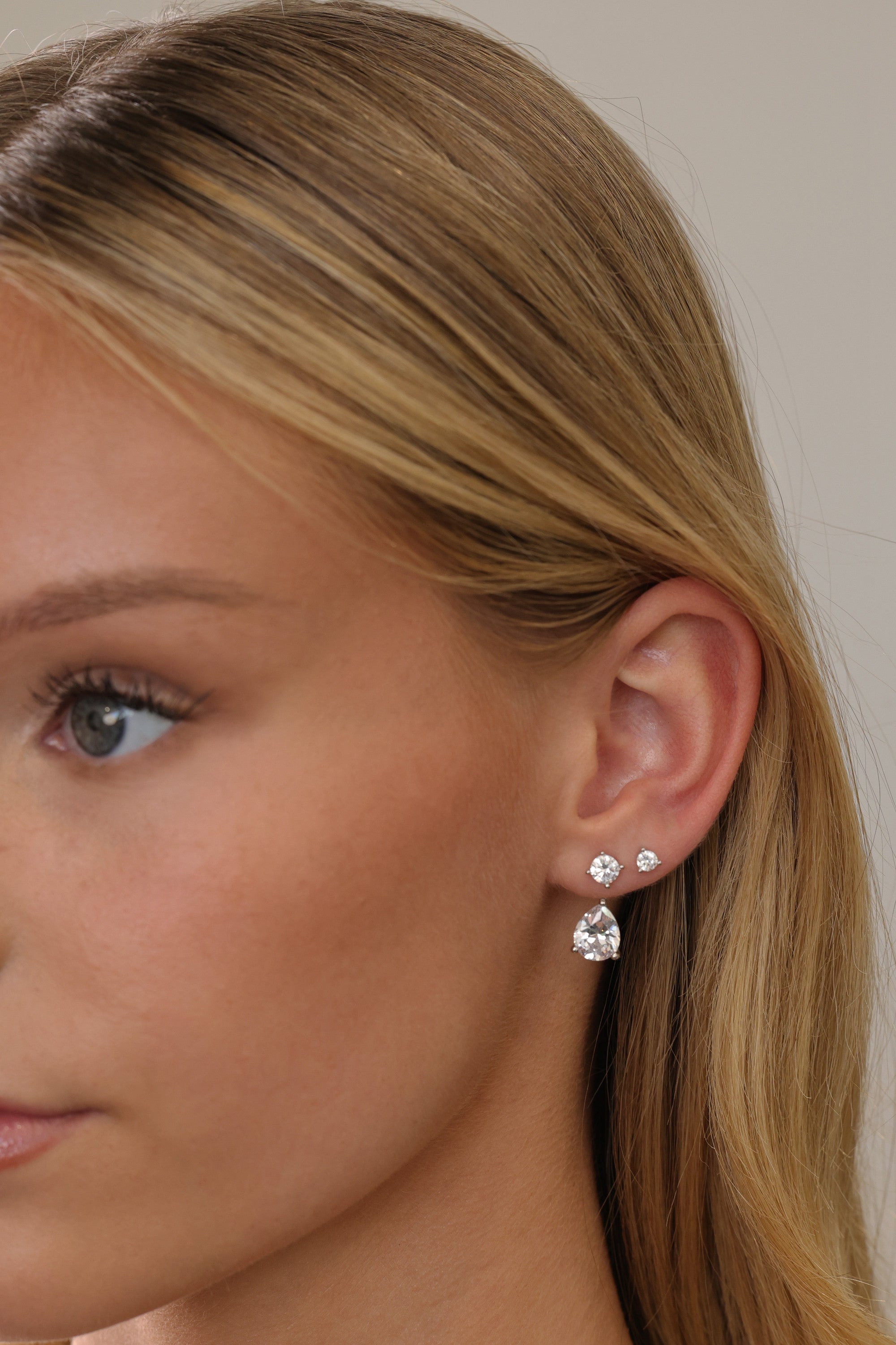 Silver Adamas ear jacket and two round studs worn together, shown in profile with hair swept back.