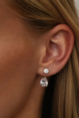Silver Adamas ear jacket worn — a round cubic zirconia stud on the lobe with the pear-cut drop hanging below it.