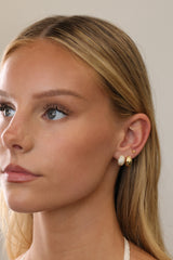 Gold Cleo Pavé and Cleo Plain huggie hoops worn together on one lobe with a small star stud above.