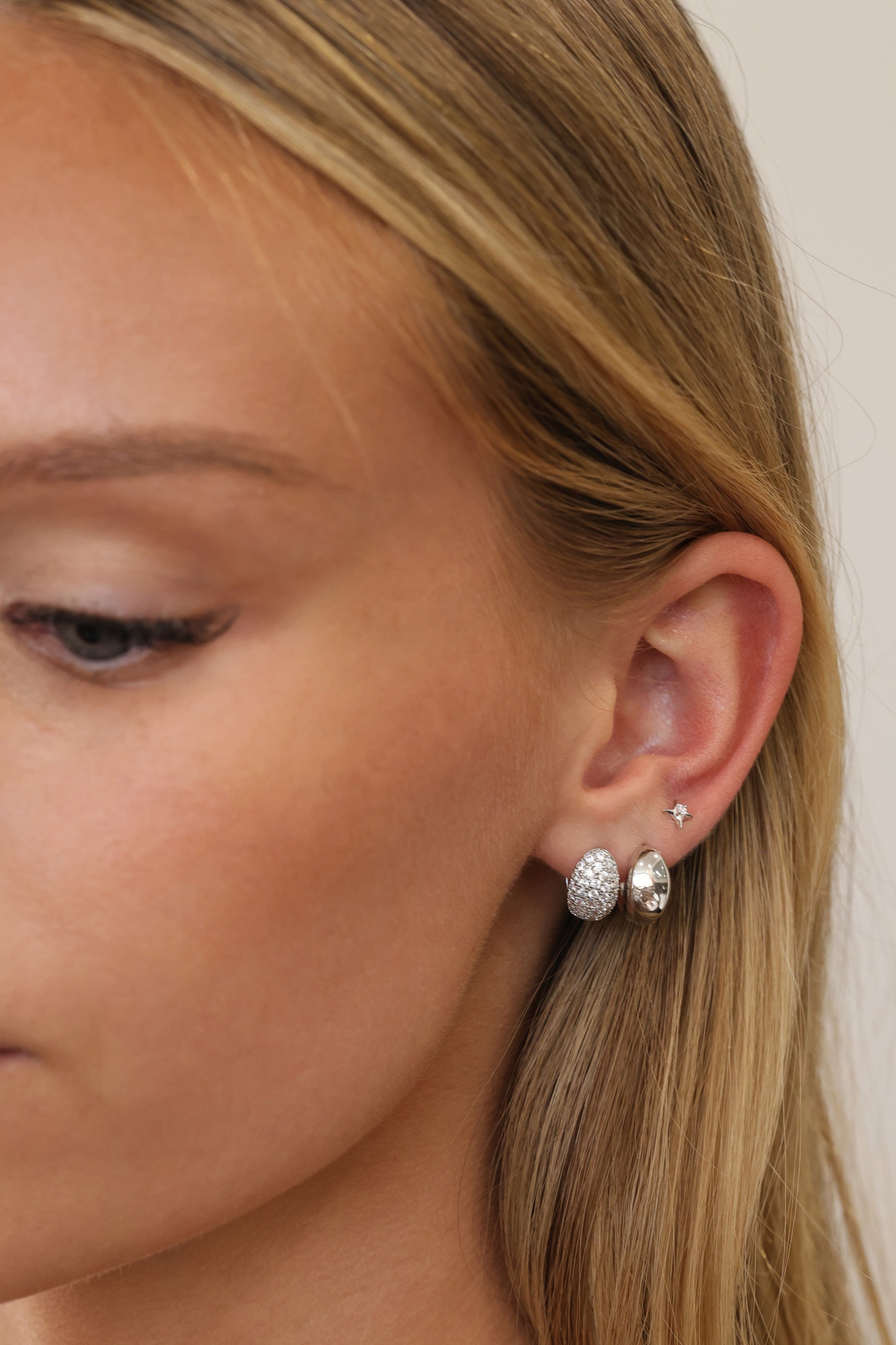 Silver Cleo Pavé and Cleo Plain huggie hoops worn on one lobe with a small star stud above.