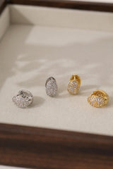 Cleo Pavé huggie hoops in gold and silver side by side in a tray, showing both metal finishes.