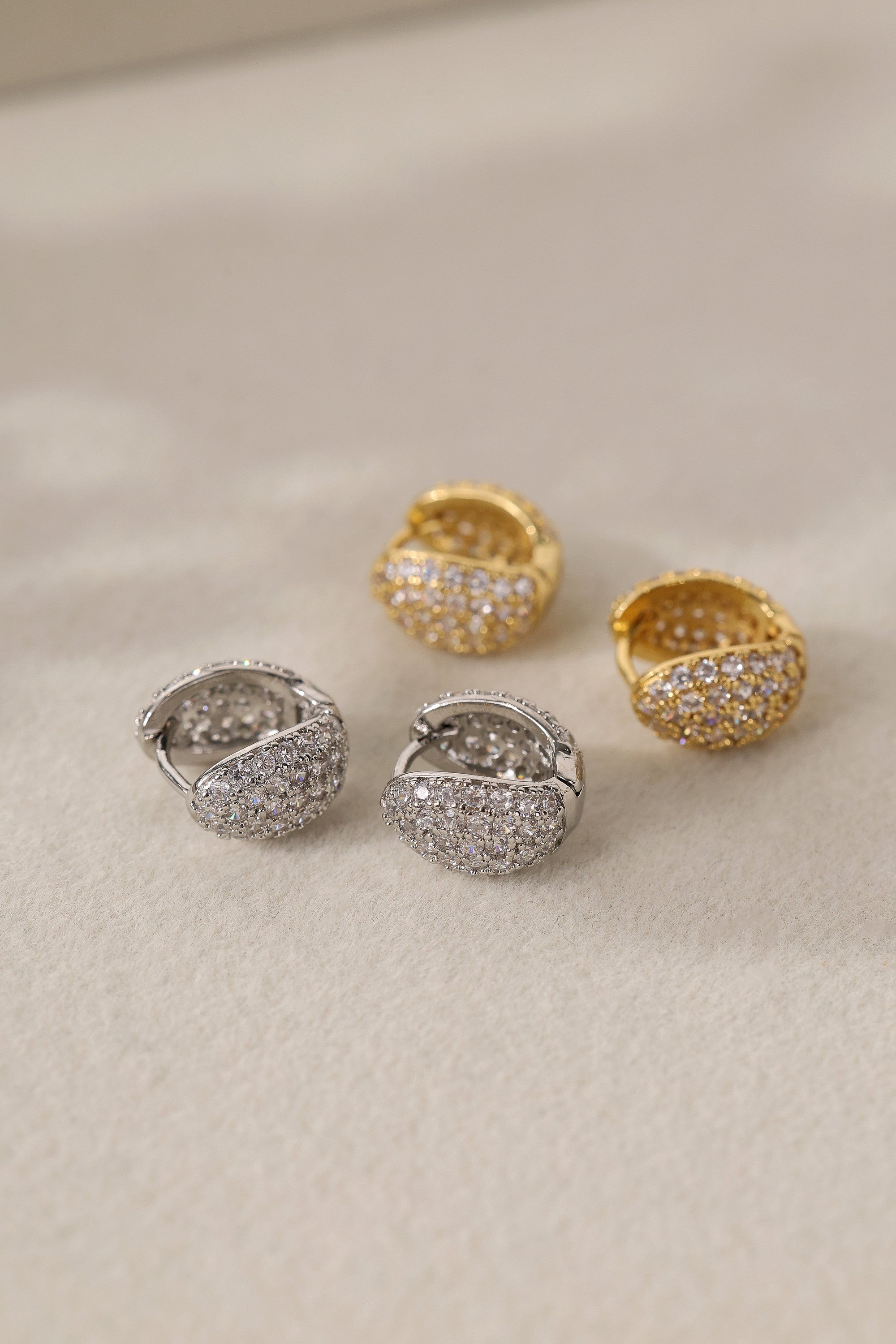 Cleo Pavé huggie hoop earrings in gold and silver — two pairs laid out together to compare finishes.