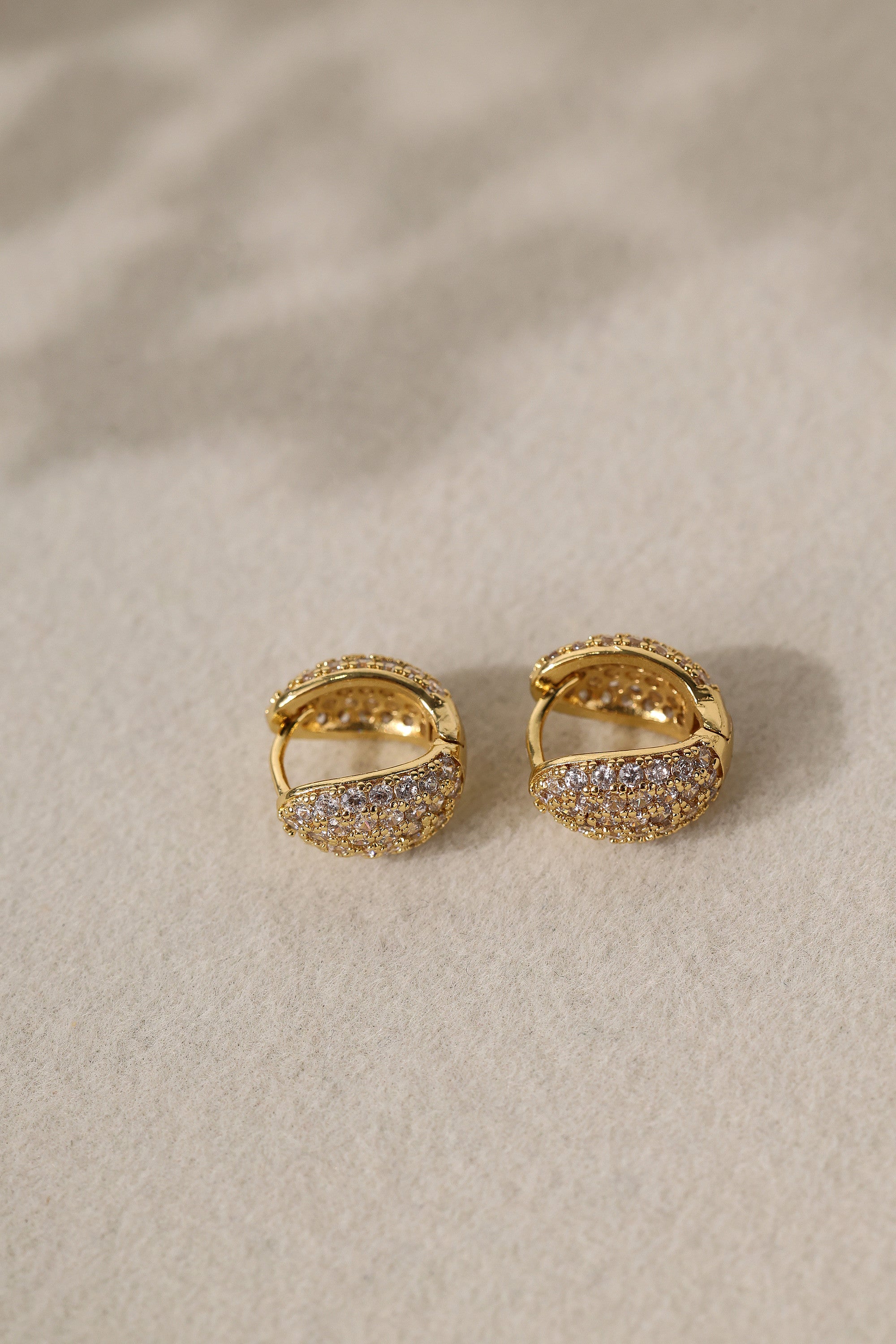 Gold Cleo Pavé huggie hoops angled to show the hinged snap closure and the 9mm hoop opening.