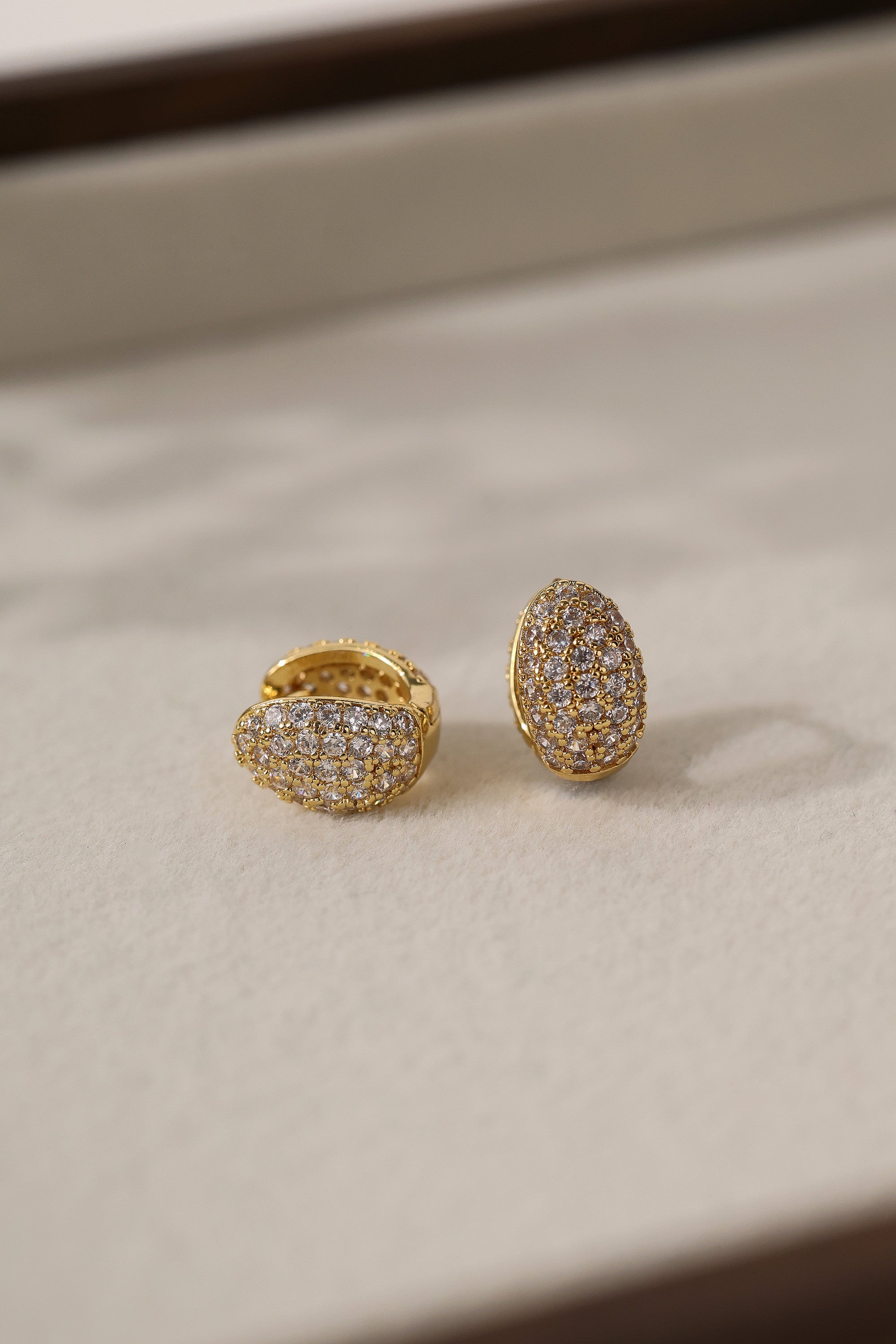 Gold Cleo Pavé huggie hoop earrings shown as a pair, one face-on — cubic zirconia set across the dome.