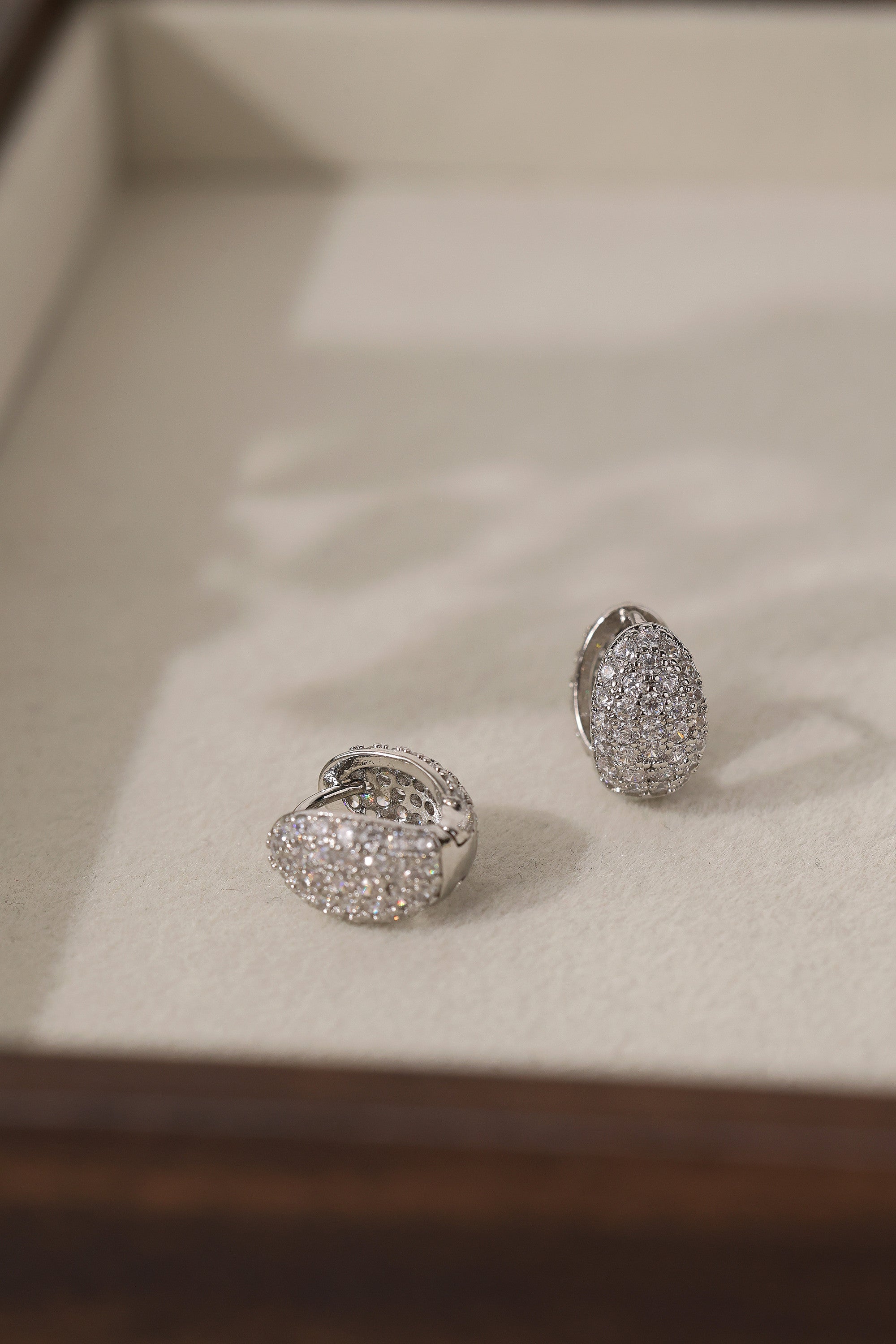 Silver Cleo Pavé huggie hoops angled to show the hinged snap closure and 9mm hoop opening.