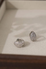 Silver Cleo Pavé huggie hoops angled to show the hinged snap closure and 9mm hoop opening.
