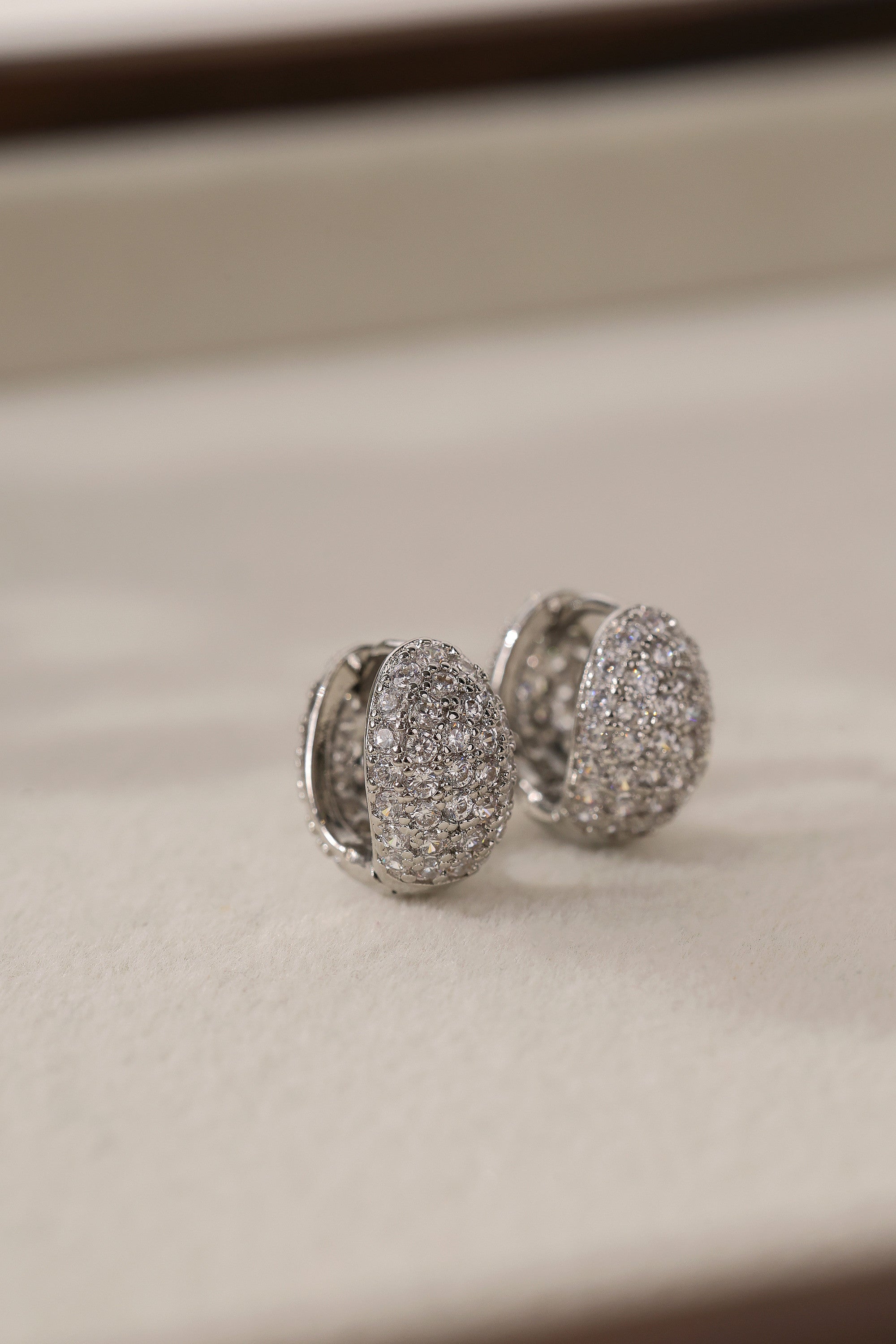 Silver Cleo Pavé huggie hoop earrings shown as a pair — cubic zirconia set across the dome.