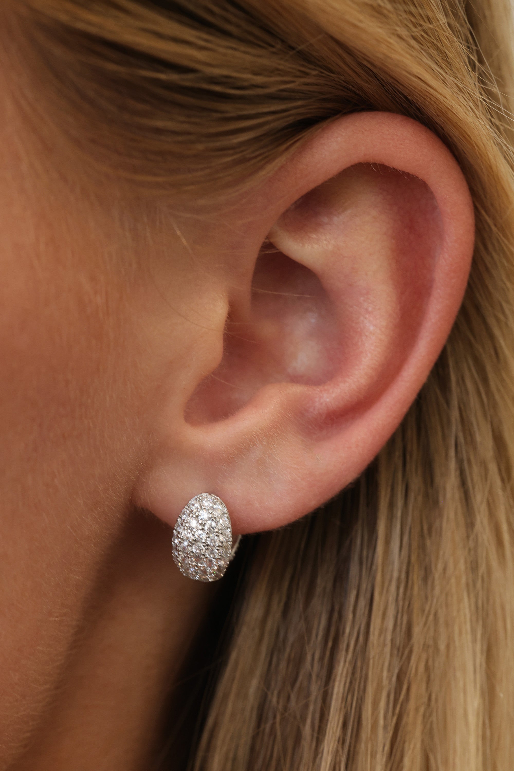 Silver Cleo Pavé huggie hoop worn on the lobe — a pavé-set cubic zirconia dome hugging the ear.