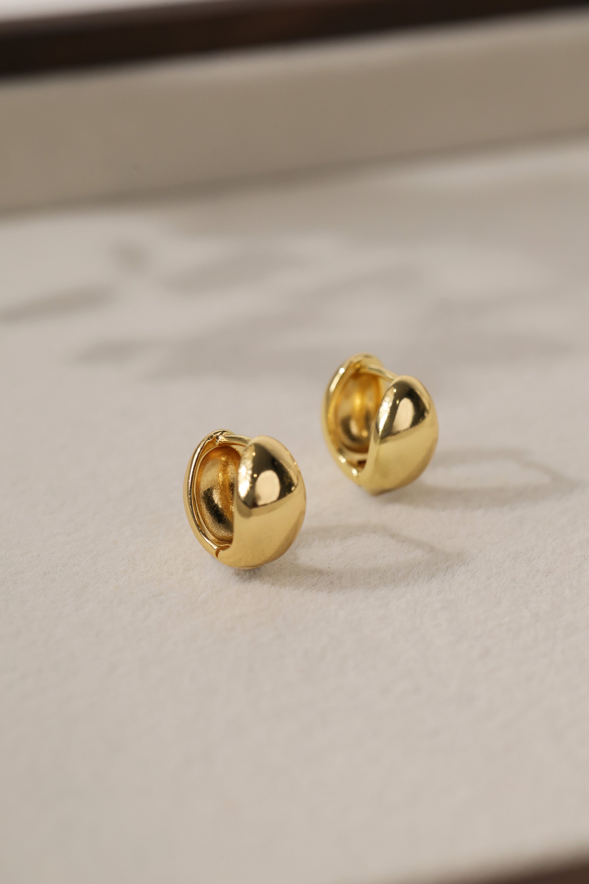 Gold Cleo Plain huggie hoop earrings as a pair — smooth polished domes with the hinge seam visible.