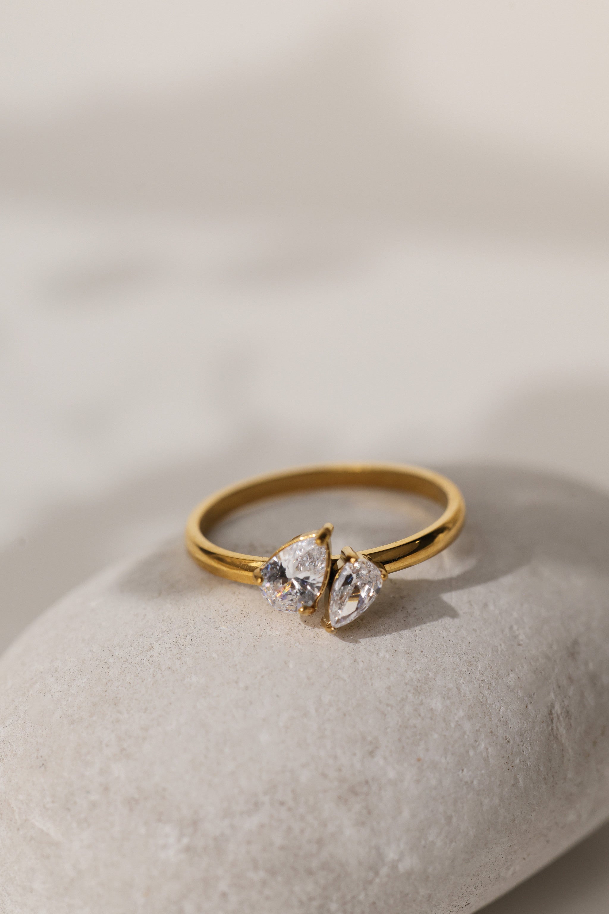 Elodie toi et moi pear ring in gold resting on a pale stone