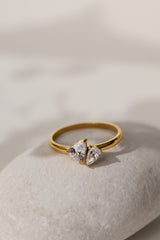 Elodie toi et moi pear ring in gold resting on a pale stone