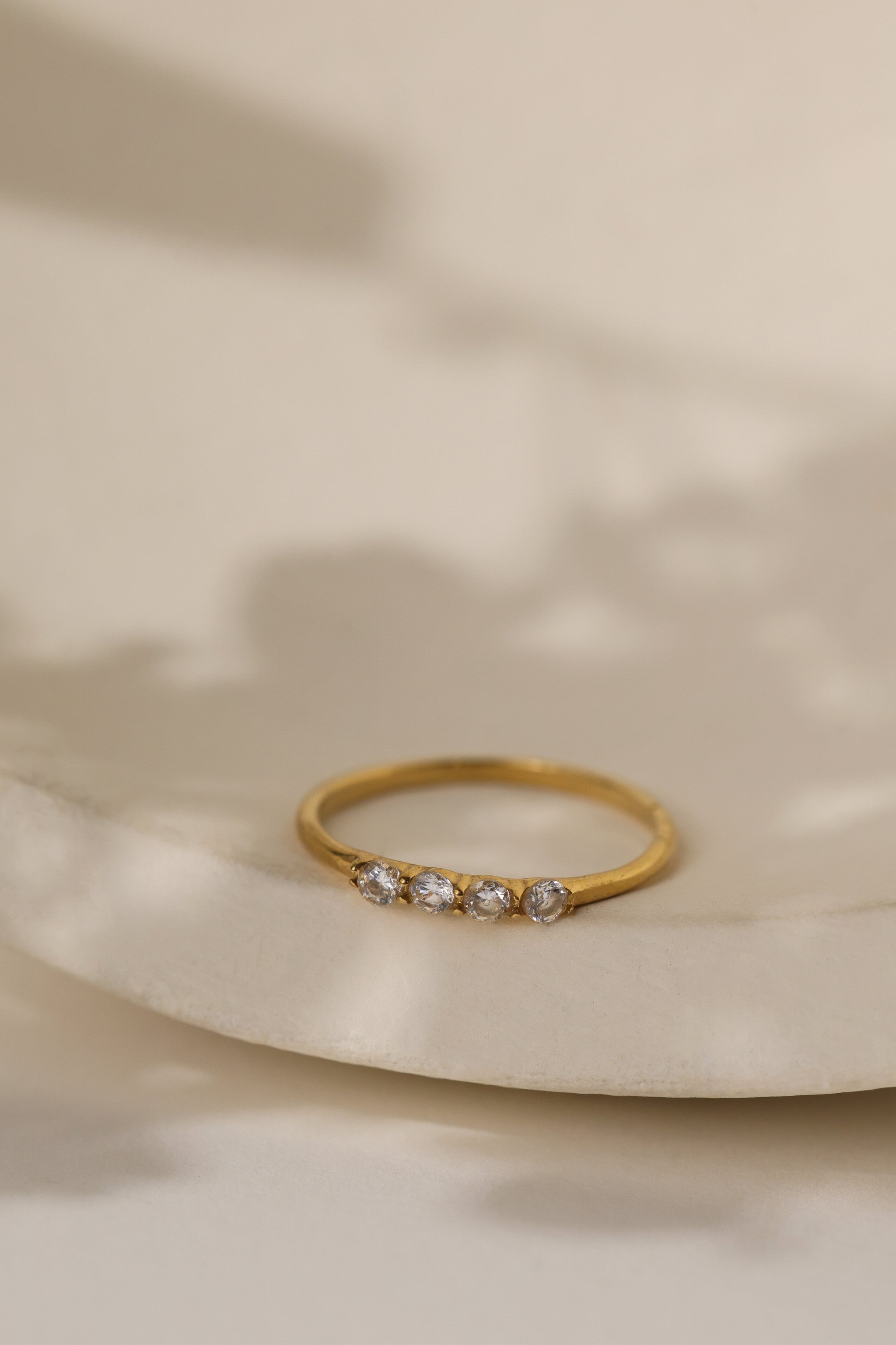 Willa four stone ring in gold on a cream ceramic dish
