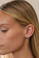Gold opal dangle huggie, pavé huggie and opal stud worn together, shown in profile with hair swept back.