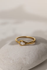 Eloise pear solitaire ring in gold resting on a pale stone