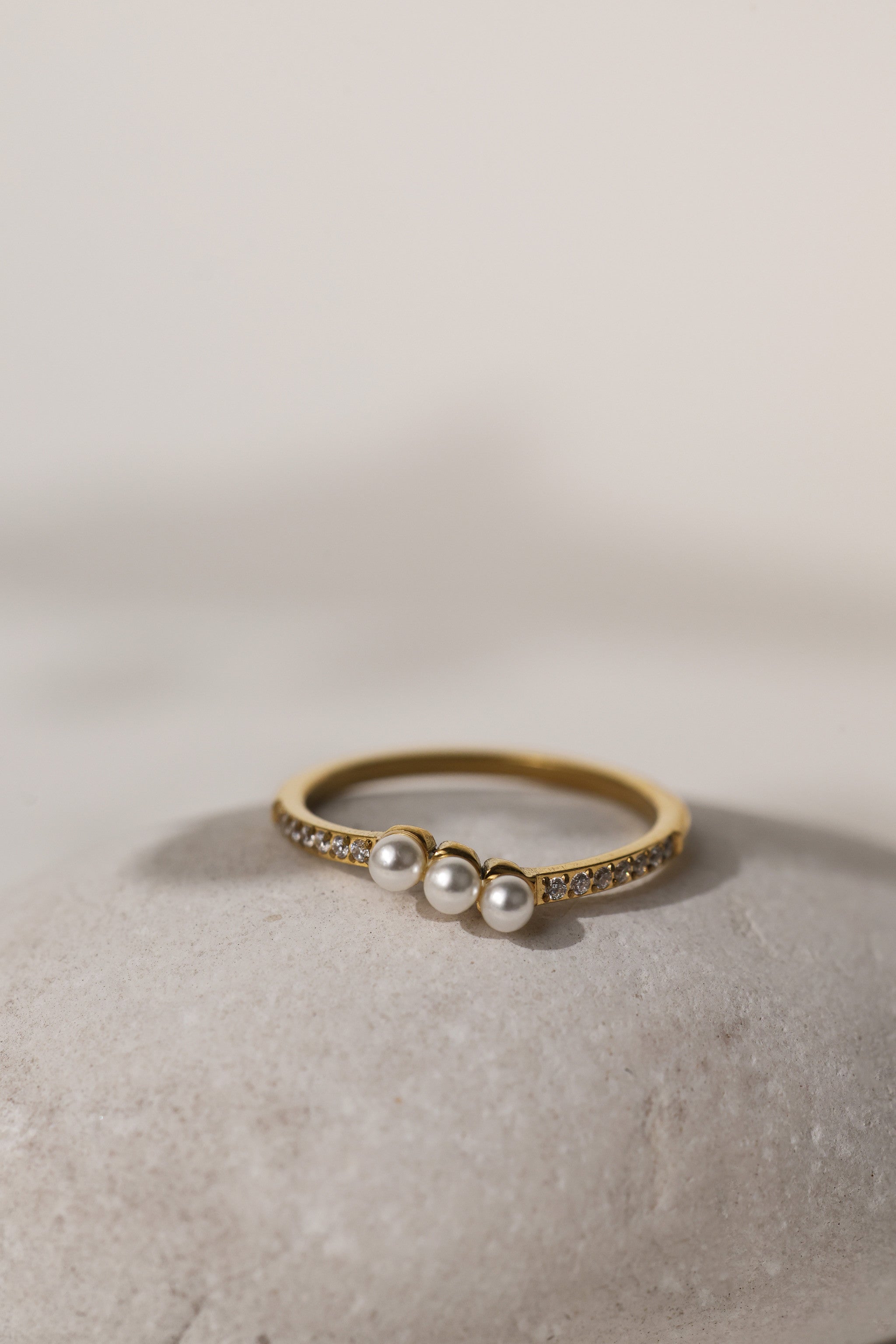 Juliette three pearl ring in gold resting on a pale stone